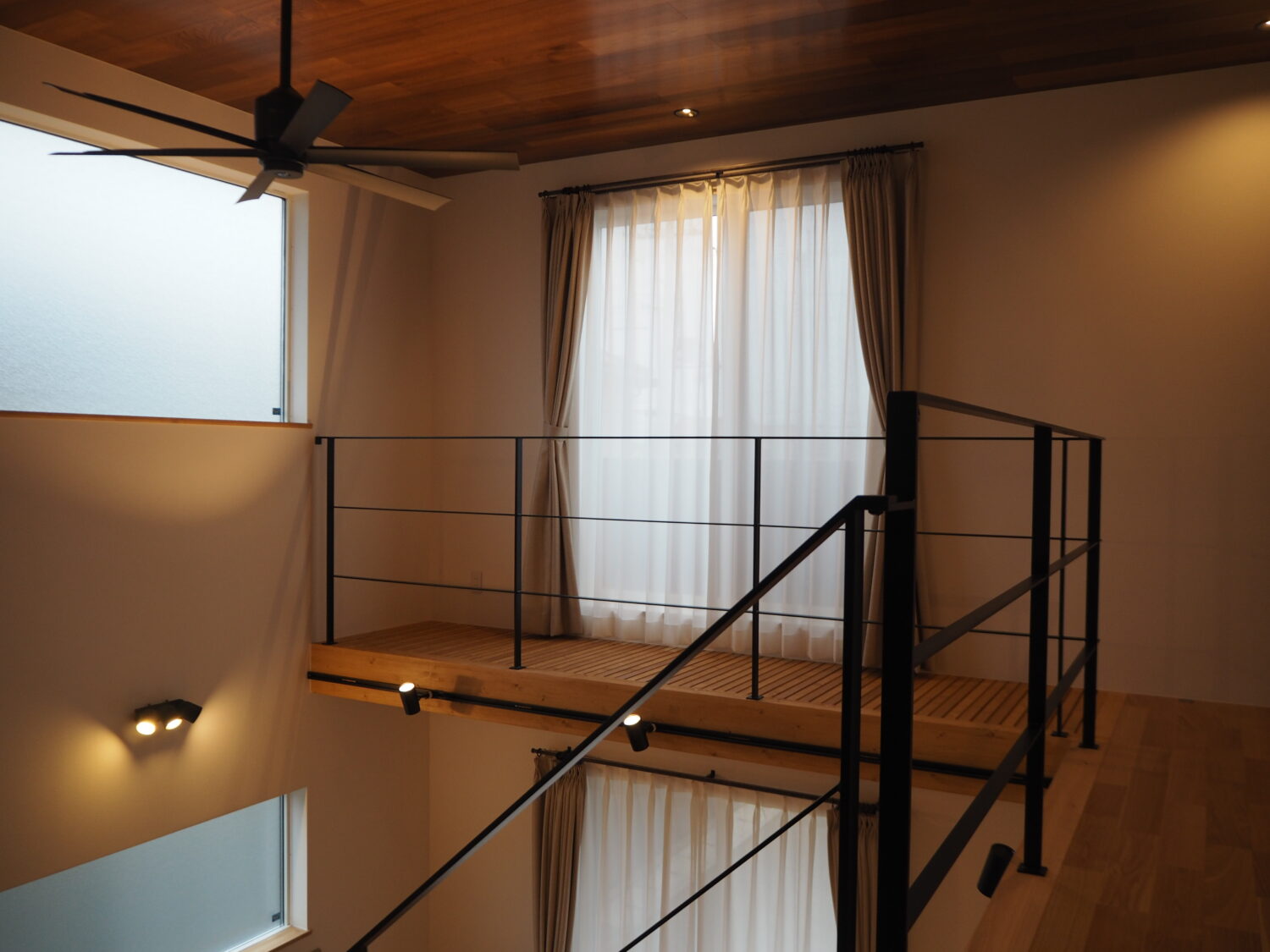 L型の吹き抜けにフラットバー手すりとシーリングファン