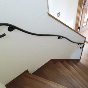 塗り壁に優雅に伸びる、曲線のアイアンてすり